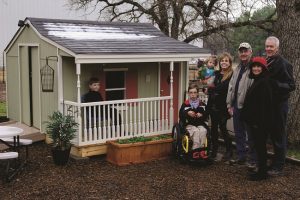 Standing next to newly-finished Bartonville playhouse include (from left) Liam Robinson, Conley Robinson, Trish Robinson holding Bella Robinson in addition to volunteer Jerry Morgan, Executive Director Sandra Monclova and Art Locke, board member, from Habitat for Humanity of Denton County.  (Photo by Bill Castleman)