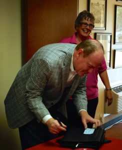 Hearts for Homes Founder Susan Frank looks on as Denton County Commissioner Andy Eads signs a $20,000 grant check for the organization (Photo Courtesy: Stacey Campbell).